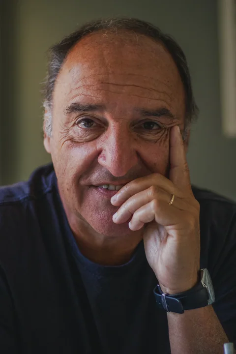 Retrato de un hombre con la mano junto a la boca y la mirada hacia la cámara