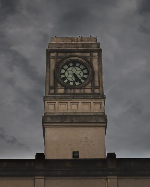 Torre de reloj de piedra recortada contra un cielo nublado
