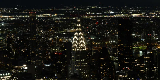 Vista nocturna de la ciudad con la cúpula iluminada del edificio Chrysler en primer plano